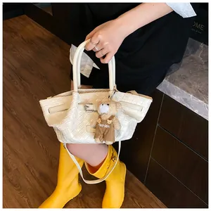 Détail du sac seau tissé blanc avec breloque ours et bandoulière réglable pratique