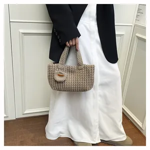 Close-up of woven waffle texture and brown leather Hand Made tag on a knitted handbag