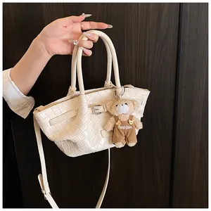 Gros plan du sac seau tissé crème avec un charmant ours en peluche et une boucle en métal