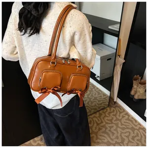 Detail of caramel tote bag featuring small front zipper pockets with satin bow accents