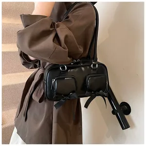 Detail of black Boston tote bag featuring twin front zipper pockets and ribbon bow accents