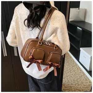 Detail of caramel glossy leather bag with silk bows and functional twin front zippers
