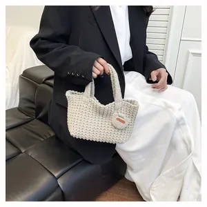Detailed close-up of woven cream handbag with Hand Made leather tag on a model