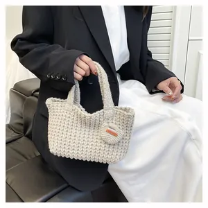 Detailed knit texture of off-white handmade handbag with heart charm and leather label