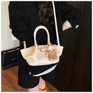 Sac seau blanc en cuir tressé avec pendentif ours porté par un mannequin élégant