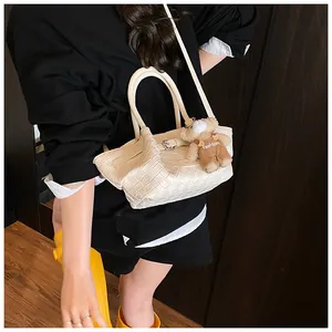 Détail du sac seau tressé ivoire avec boucle métallique et breloque ours en peluche