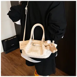 Détail du sac seau blanc tressé avec boucle métallique et pendentif ours en peluche