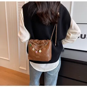 Sac seau matelassé marron avec chaîne dorée et breloque, vue arrière sur modèle