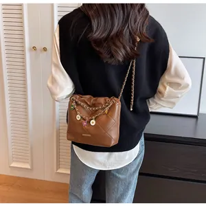 Détail d'un sac seau matelassé marron avec breloques cœurs et bandoulière chaîne