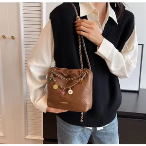 Détail du sac seau en cuir matelassé marron avec pendentifs cœur et bandoulière en chaîne