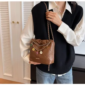 Gros plan du sac seau matelassé marron avec breloques cœurs colorés et chaîne dorée