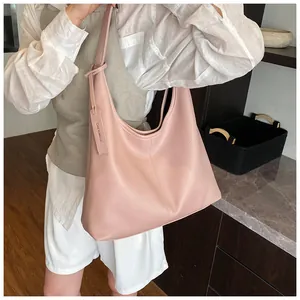 Grand sac cabas rose en cuir lychee porté par un mannequin pour un look quotidien chic