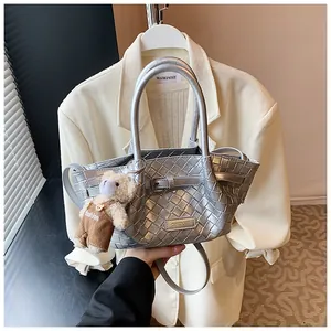 Détail du sac seau tissé argenté avec bandoulière réglable et breloque ourson
