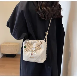 Sac seau matelassé beige avec breloques cœur colorées porté sur un manteau noir