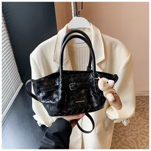 Détail du sac seau tissé noir avec breloque ours et doubles bandoulières