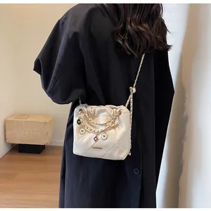 Détail du sac seau matelassé avec cordons et breloques en forme de cœur sur un mannequin
