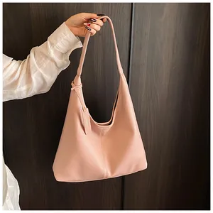 Gros plan du sac hobo rose avec texture cuir litchi souple et étiquette de marque