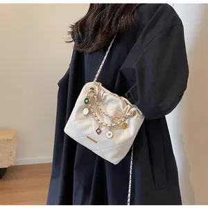 Détail du sac seau matelassé blanc orné de breloques en cœur colorées et bandoulière chaîne