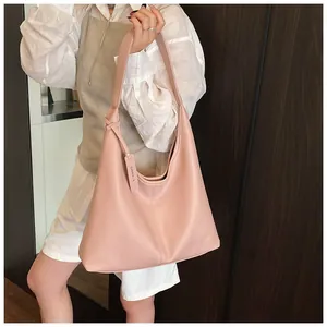 Détail du sac Hobo en cuir rose clair à motif litchi sur l'épaule d'un mannequin femme