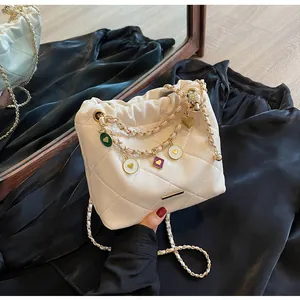 Détail d'un sac seau matelassé blanc avec breloques cœurs colorés et chaîne dorée
