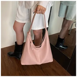 Détail d'un sac cabas rose en cuir grainé montrant l'étiquette et la texture raffinée