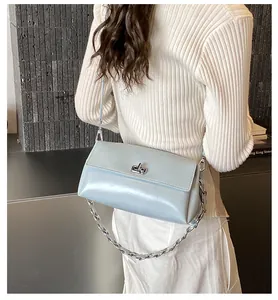 Détail du sac en cuir brillant bleu clair avec chaîne argentée porté à l'épaule