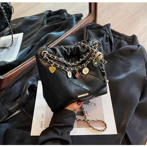Détail du sac seau noir en cuir matelassé avec chaîne dorée et breloques colorées