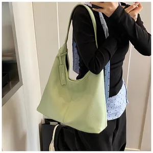 Gros plan d'un sac cabas en cuir vert clair à texture litchi porté par un mannequin