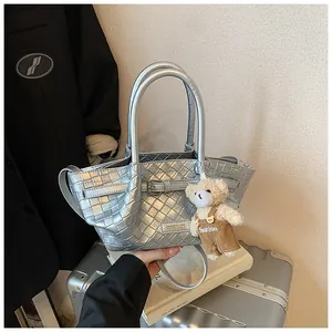 Détail du sac seau tressé argenté avec finition métallique et pendentif ours mignon