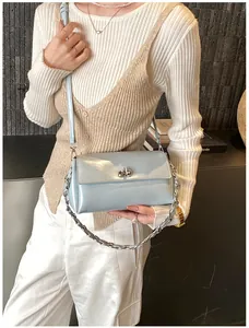 Détail du sac à rabat en cuir verni bleu clair avec chaîne argentée et fermoir pivotant