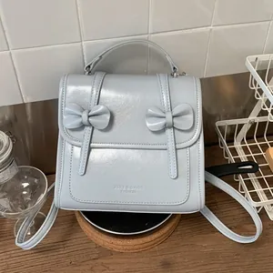 Sac à dos bleu clair brillant pour femme avec nœuds décoratifs et poignée supérieure chic