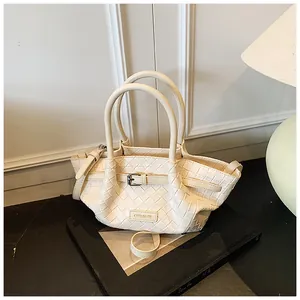 Détail du sac seau tressé crème avec logo CHERIMATE et boucle décorative chic