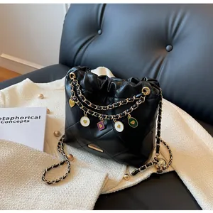 Détail du sac seau noir matelassé avec chaînes dorées et breloques en émail coloré