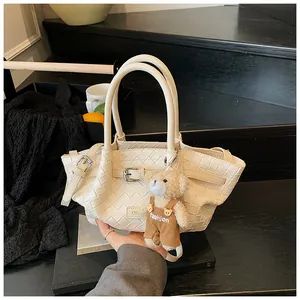 Détail d'un sac seau tressé crème avec un charmant pendentif en forme d'ourson
