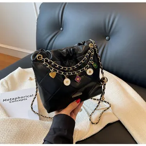 Détail du sac seau noir matelassé avec chaînes dorées et breloques émaillées colorées