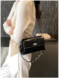 Détail montrant la texture en cuir verni brillant et la chaîne argentée du sac noir