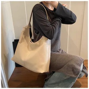 Détail macro de la texture en cuir grainé beige sur un grand sac à main de style hobo
