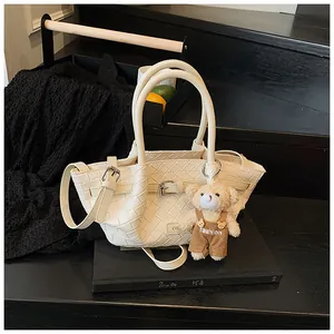 Détail du sac seau tissé blanc avec charm ours sur un fond esthétique sombre et chic
