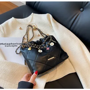 Détail du sac seau matelassé noir avec chaîne dorée et breloques en émail cœur