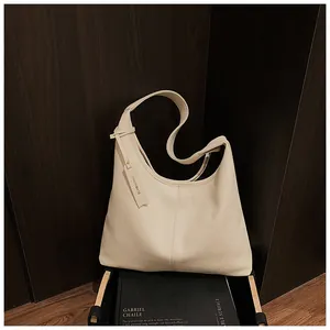 Gros plan sur le sac cabas en cuir litchi crème avec étiquette sur un livre d'art