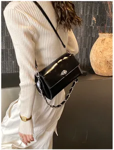Détail du sac bandoulière noir brillant avec fermoir argenté et bandoulière chaîne