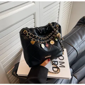 Détail du sac seau noir matelassé avec chaîne dorée et breloques cœur colorées