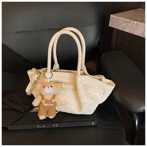 Sac panier tressé blanc cassé tendance avec charme d'ours sur siège en cuir noir