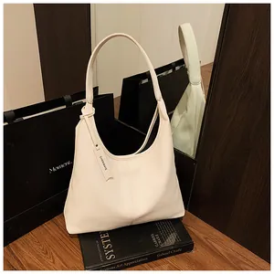 Détail de la texture cuir grainé du sac hobo beige avec une étiquette de marque décorative