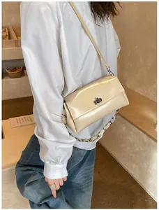 Détail du sac sous le bras en cuir verni crème avec fermoir rotatif et chaîne argent