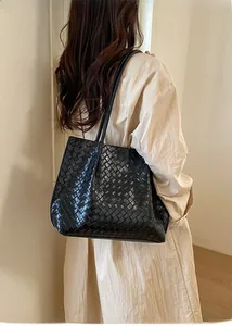 Détail d'un grand sac cabas noir en cuir tressé avec bandoulière élégante pour femme