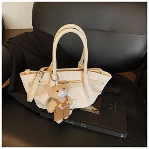Détail du sac seau tressé crème avec texture à carreaux et pendentif ours mignon