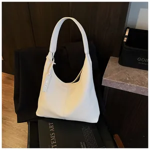 Gros plan du sac fourre-tout blanc texturé litchi sur un blazer noir dans un décor chic