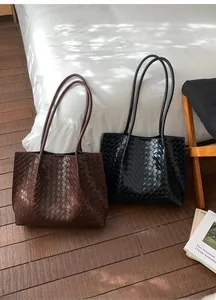 Détail de la texture en cuir tressé sur des sacs cabas noirs et marrons en décor intérieur