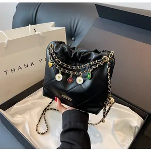 Vue détaillée du sac seau noir matelassé avec chaîne dorée et charms en émail colorés